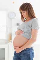 Good looking pregnant woman posing while caressing her belly
