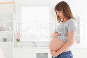 Attractive pregnant woman posing while caressing her belly