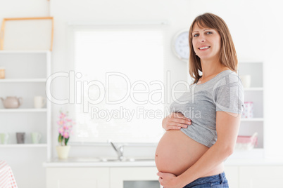 Gorgeous pregnant woman posing while caressing her belly