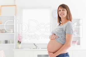Gorgeous pregnant woman posing while caressing her belly