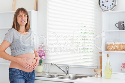 Gorgeous pregnant female posing while caressing her belly