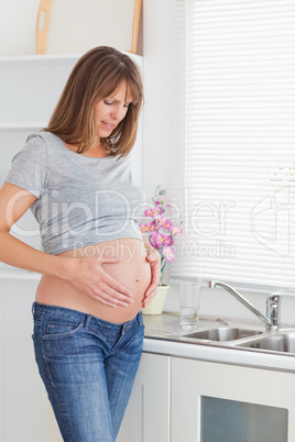 Beautiful pregnant female posing while caressing her belly