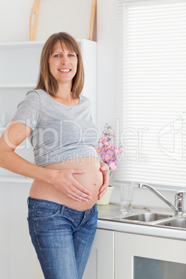 Attractive pregnant female posing while caressing her belly