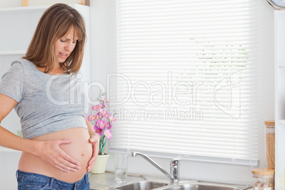 Good looking pregnant female posing while caressing her belly