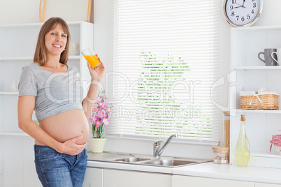 Attractive pregnant woman holding a glass of orange juice while