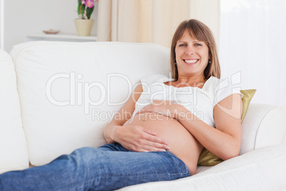 Good looking pregnant woman posing while lying on a sofa