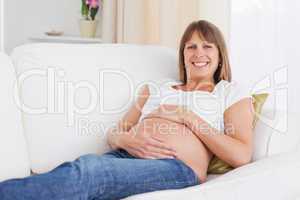 Good looking pregnant woman posing while lying on a sofa