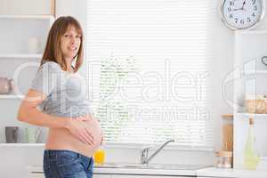 Beautiful pregnant woman caressing her belly while standing