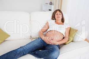 Beautiful pregnant woman posing while lying on a sofa