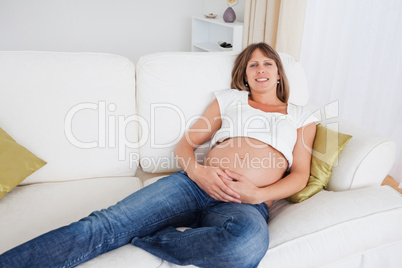 Attractive pregnant woman posing while lying on a sofa