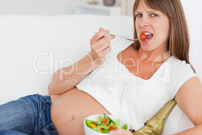 Close up of a happy pregnant woman eating a salad