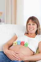 Lovely pregnant woman playing with wooden blocks while lying on