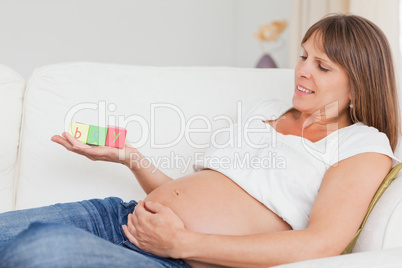 Attractive pregnant woman playing with wooden blocks and having