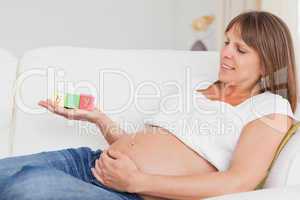 Attractive pregnant woman playing with wooden blocks and having