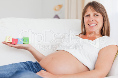 Good looking pregnant woman playing with wooden blocks and havin