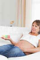 Good looking pregnant woman playing with wooden blocks and havin