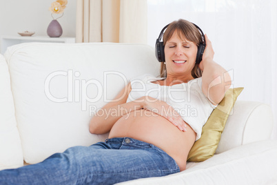 Happy pregnant woman listening to music