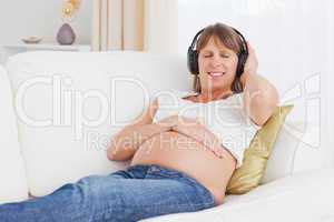 Happy pregnant woman listening to music