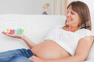 Beautiful pregnant woman playing with wooden blocks and having t