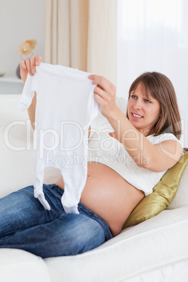 Attractive pregnant woman holding a baby grow while lying on a s