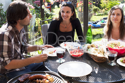 Drei Personen bei Gartenparty mit Grillen