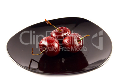 cherries on a black saucer isolated on white