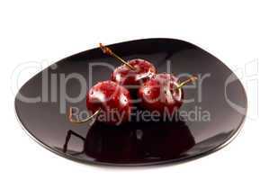 cherries on a black saucer isolated on white