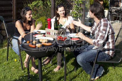 Drei Personen bei Gartenparty mit Grillen