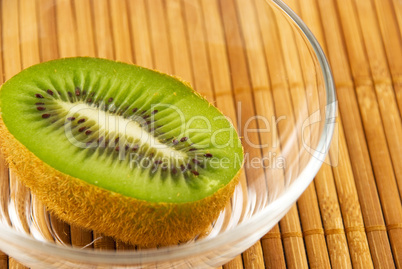 kiwi fruit in a glass bowl on a bamboo mat