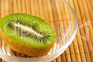 kiwi fruit in a glass bowl on a bamboo mat