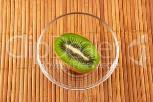 kiwi fruit in a glass bowl on a bamboo mat