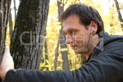 man with headphones standing near the tree