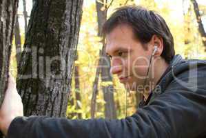 man with headphones standing near the tree