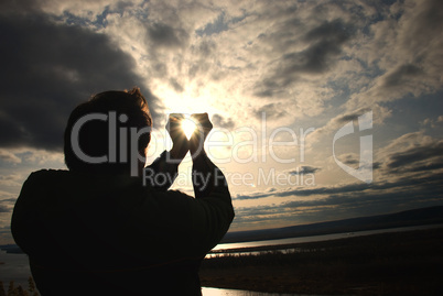 man holding a sun in his hands against the sky