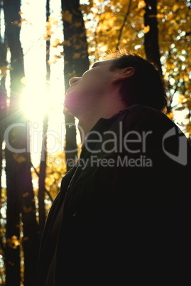 man looking at the sun in the autumn forest