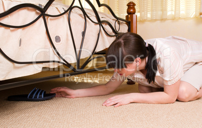 Woman gets sneakers from under the bed