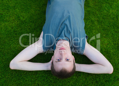 The young man lies on a green grass