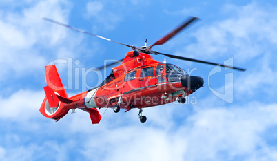 Red rescue helicopter moving in blue sky