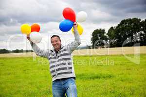 Mann mit Luftballons freut sich 582
