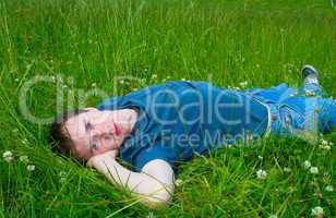 The young man lies on a green meadow