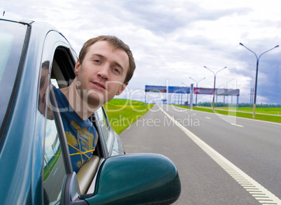 The young man looks out of a car window on road