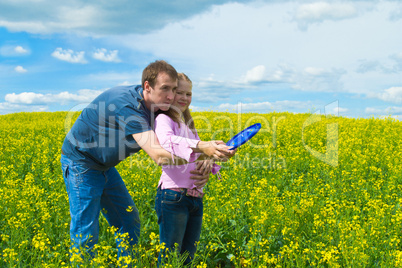 The father learns a daughter to launch frisbee on a meadow