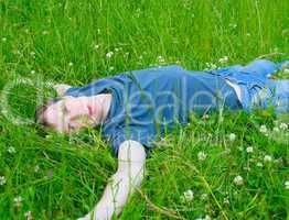 The young man lies on a green grass