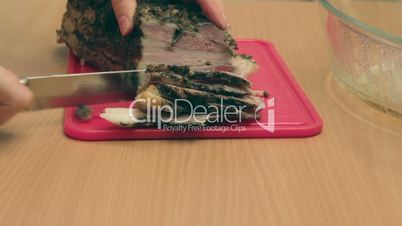 Carving fat piece of  baked pork into thin slices