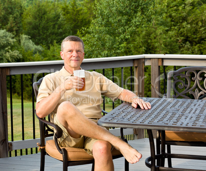 Senior man drinking beer in garden