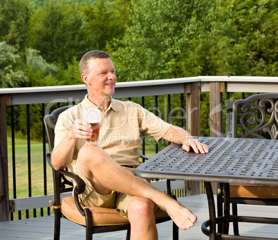 Senior man drinking beer in garden