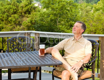Senior man drinking beer in garden