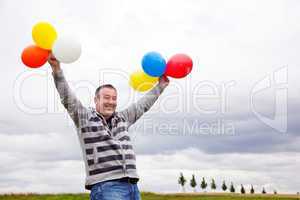 Mann mit Luftballons freut sich 588