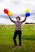 Frau mit Luftballons auf der Wiese freut sich 569