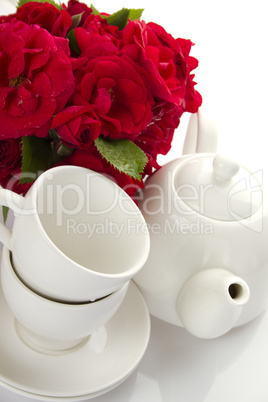 White crockery for tea and a bouquet of roses